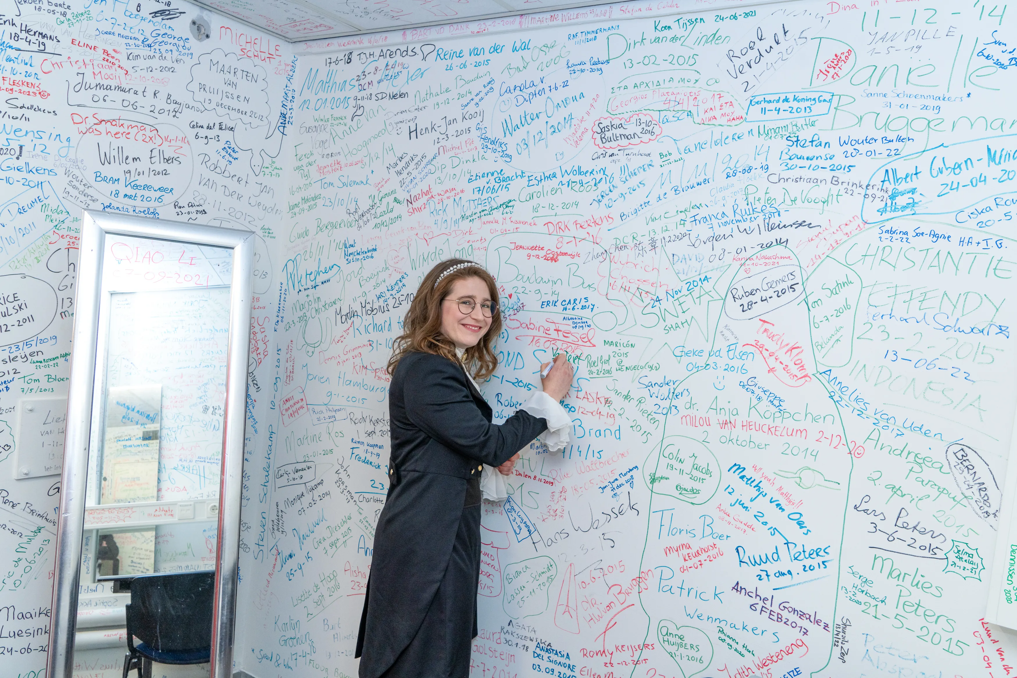 Promovenda zet haar handtekening op de muur van de Cella Sudatoria van de Radboud Universiteit